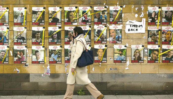 A woman passes by a wall with photos of hostages held by Hamas in the Gaza Strip on Jan. 30, 2024, in Tel Aviv, Israel. The Israeli prime minister's office referred to as 'constructive' the recent high-level talks on a proposed pause in fighting in Gaza, as well the release of Israeli hostages held there. The potential deal, which is being brokered by Qatar and Egypt, would also entail the release of Palestinian prisoners held in Israel and other conditions. (Amir Levy/Getty Images/TNS)