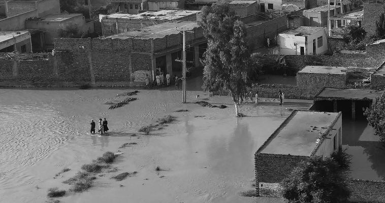 Residents wade through a flood hit area following heavy monsoon rains in Charsadda district of Khyber Pakhtunkhwa on Aug. 29, 2022. - The death toll from monsoon flooding in Pakistan since June has reached 1,061, according to figures released on Aug. 29, 2022, by the country's National Disaster Management Authority. (Abdul Majeed/AFP via Getty Images/TNS)