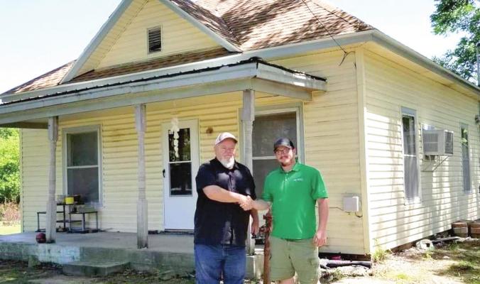 GETTING BACK TO BIZ — Jerry Bright, left, shakes the hand of James Brocaw, with H&amp;H Roofing and Restoration, LLC, Independence, following the completion of a new roof on a home. Bright said Community Mission for Improved Housing is back up and ready for business.Courtesy Photo
