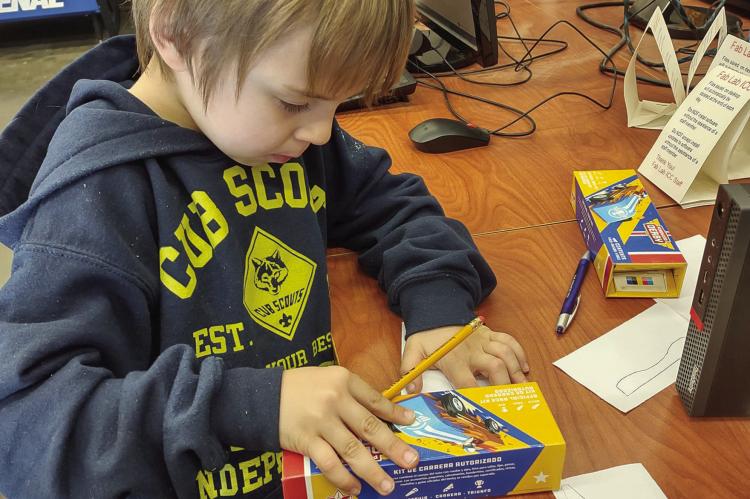 Concentrating hard, this Cub Scout works on perfecting his derby car.