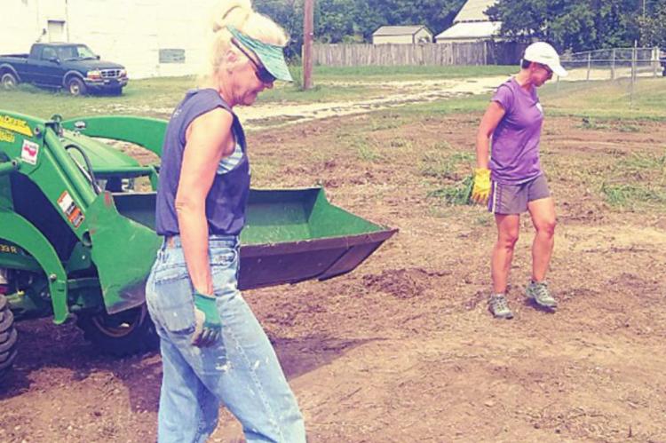 WORKING FOR THE COMMUNITY — Anne Hogsett, left, and Jodi Hayse, right, search the ground for unwanted items while preparing for another community orchard.